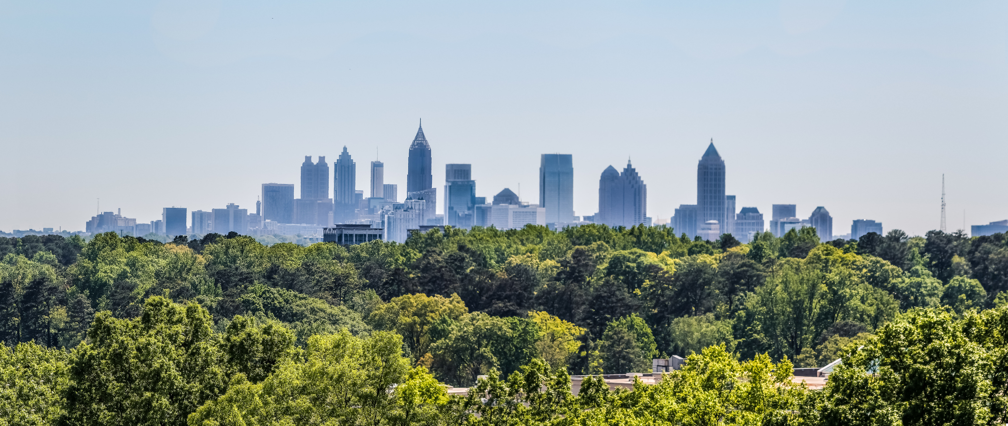 Downtown Atlanta Skyline showing several prominent buildings and hotels under a blue sky as seen from Buckhead in North Atlanta